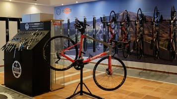 A bicycle display with a red bike on a stand, a wall-mounted bike rack, and a cycling-themed poster.