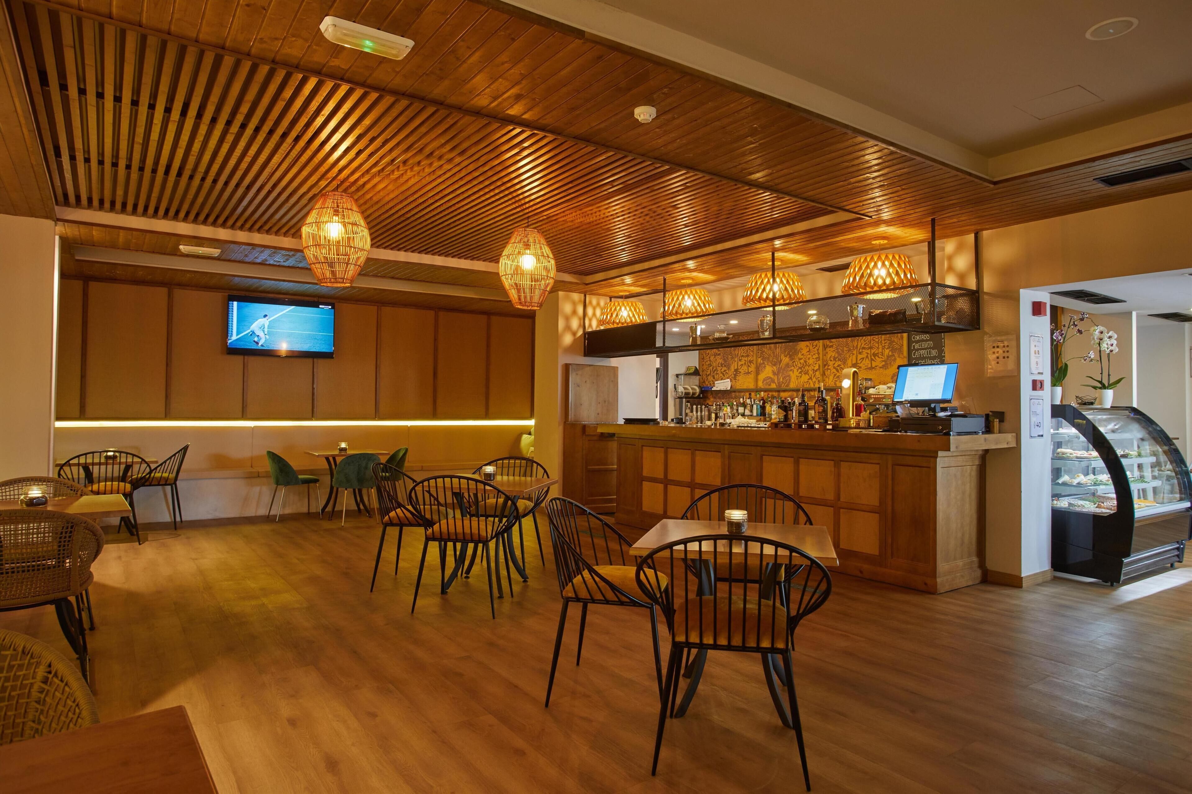 Un restaurant doté d’un plancher en bois, de chaises en osier, d’un bar avec un comptoir vitré et d’un téléviseur fixé au mur.