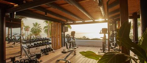An outdoor gym with exercise equipment, a view of the ocean, and a wooden deck.