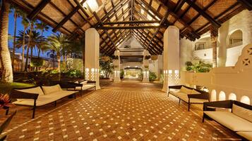 An indoor area with a patterned floor, wooden beams, and seating arrangements.