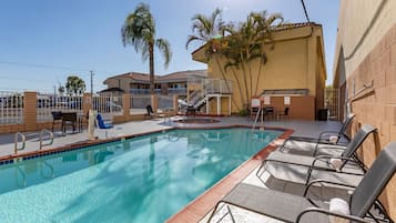 Una piscina al aire libre, sombrillas, sillones reclinables de piscina