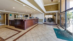 A hotel lobby with a reception desk, a dining area, and a view of the outdoors.