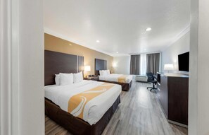 Une chambre d’hôtel avec deux lits, un bureau, une chaise et un téléviseur.