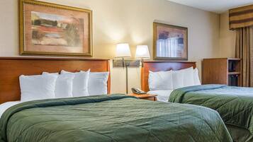 A hotel room with two beds, a wooden headboard, a nightstand with a lamp, a telephone, and a cabinet.