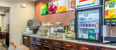 A breakfast bar with a refrigerator, microwave, and various food items.