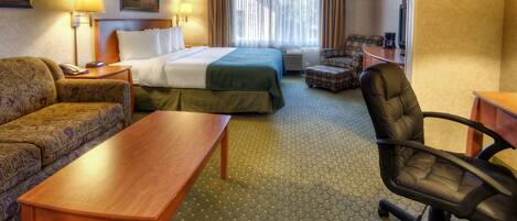 A hotel room with a bed, a sofa, a desk, a chair, and a lamp.
