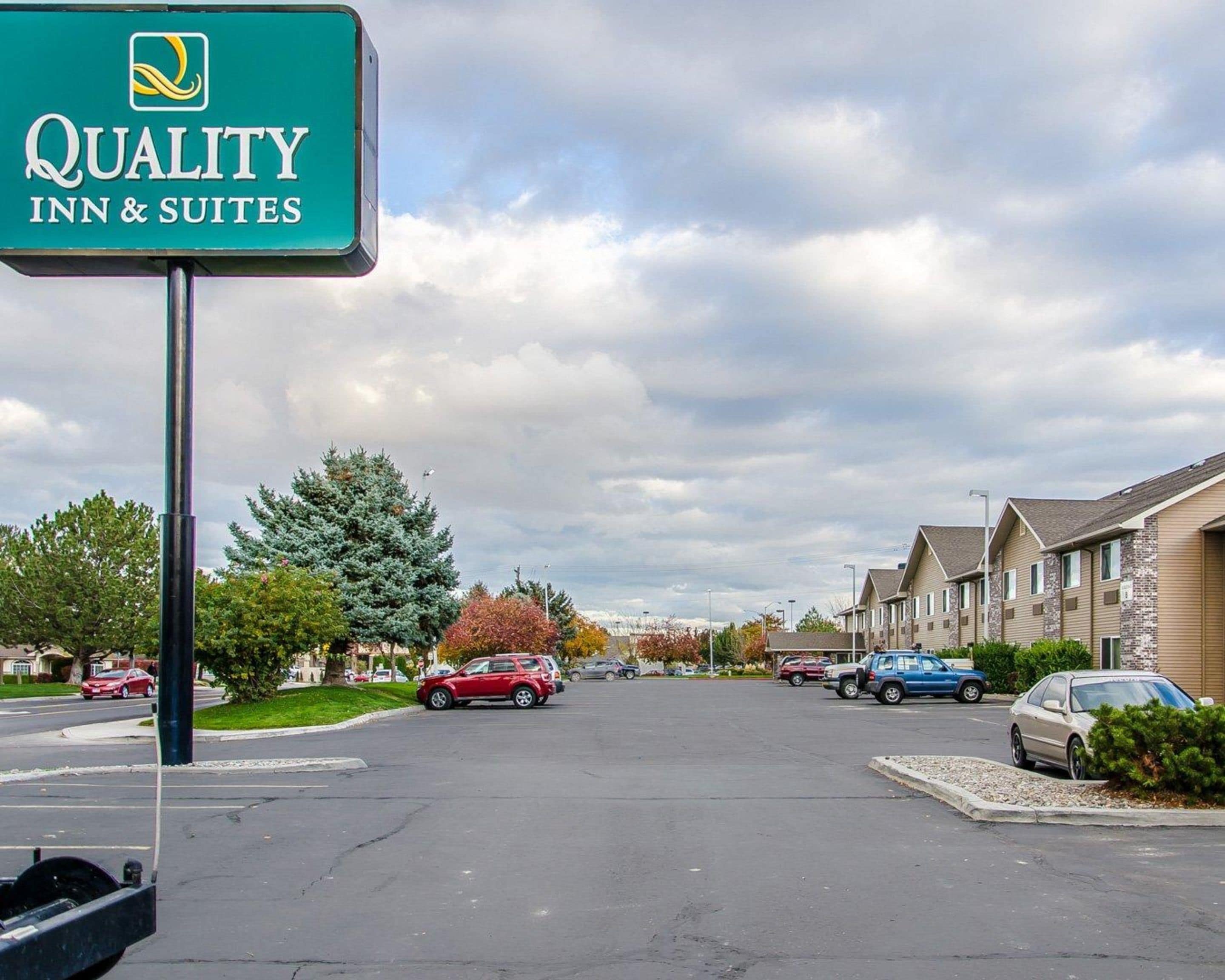 Señal de Quality Inn & Suites en un estacionamiento, con edificios residenciales al fondo.