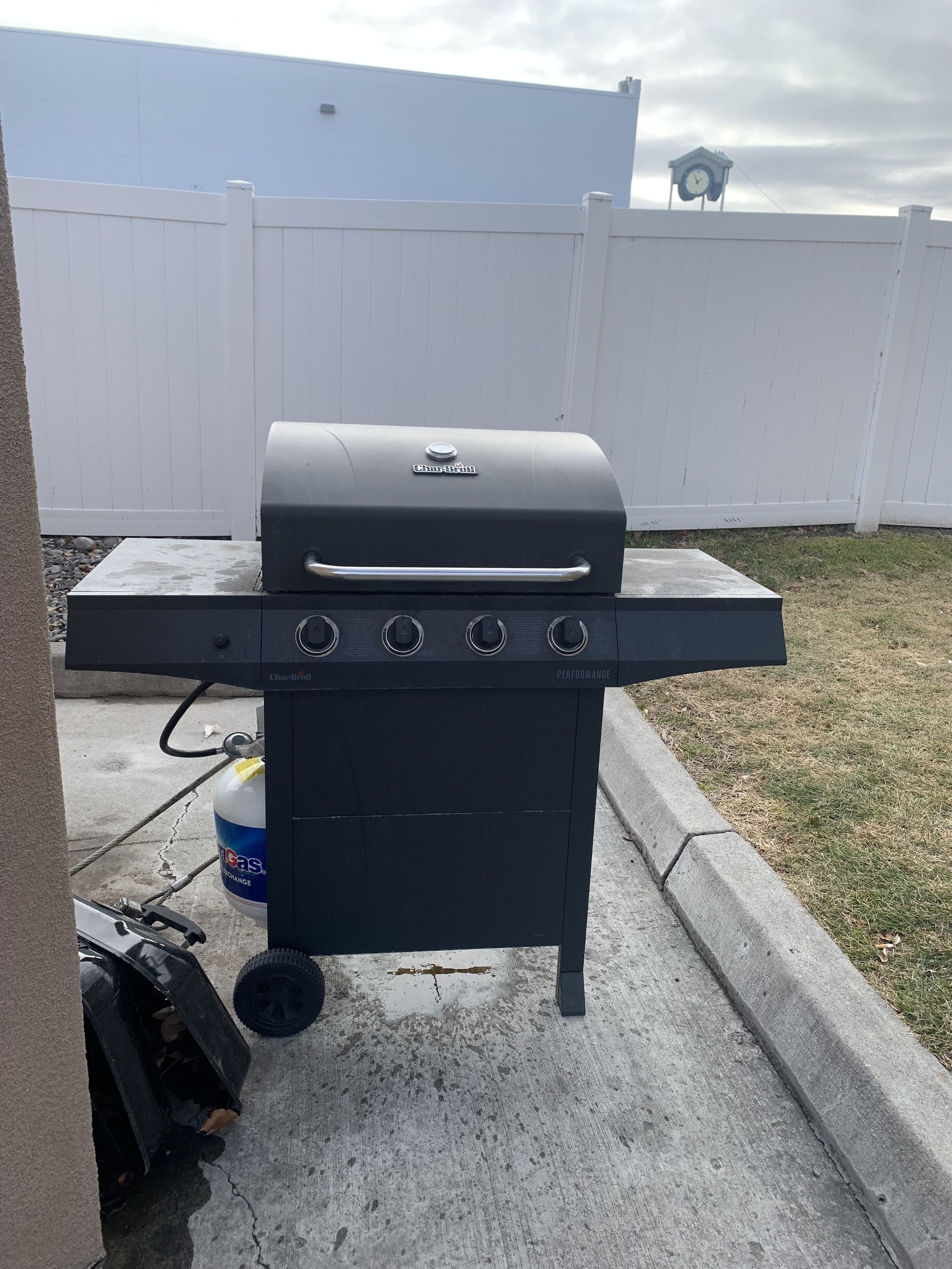 A Char-Broil gas grill with four burners, a side shelf, and a gas tank.