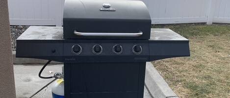 A Char-Broil gas grill with four burners, a side shelf, and a gas tank.