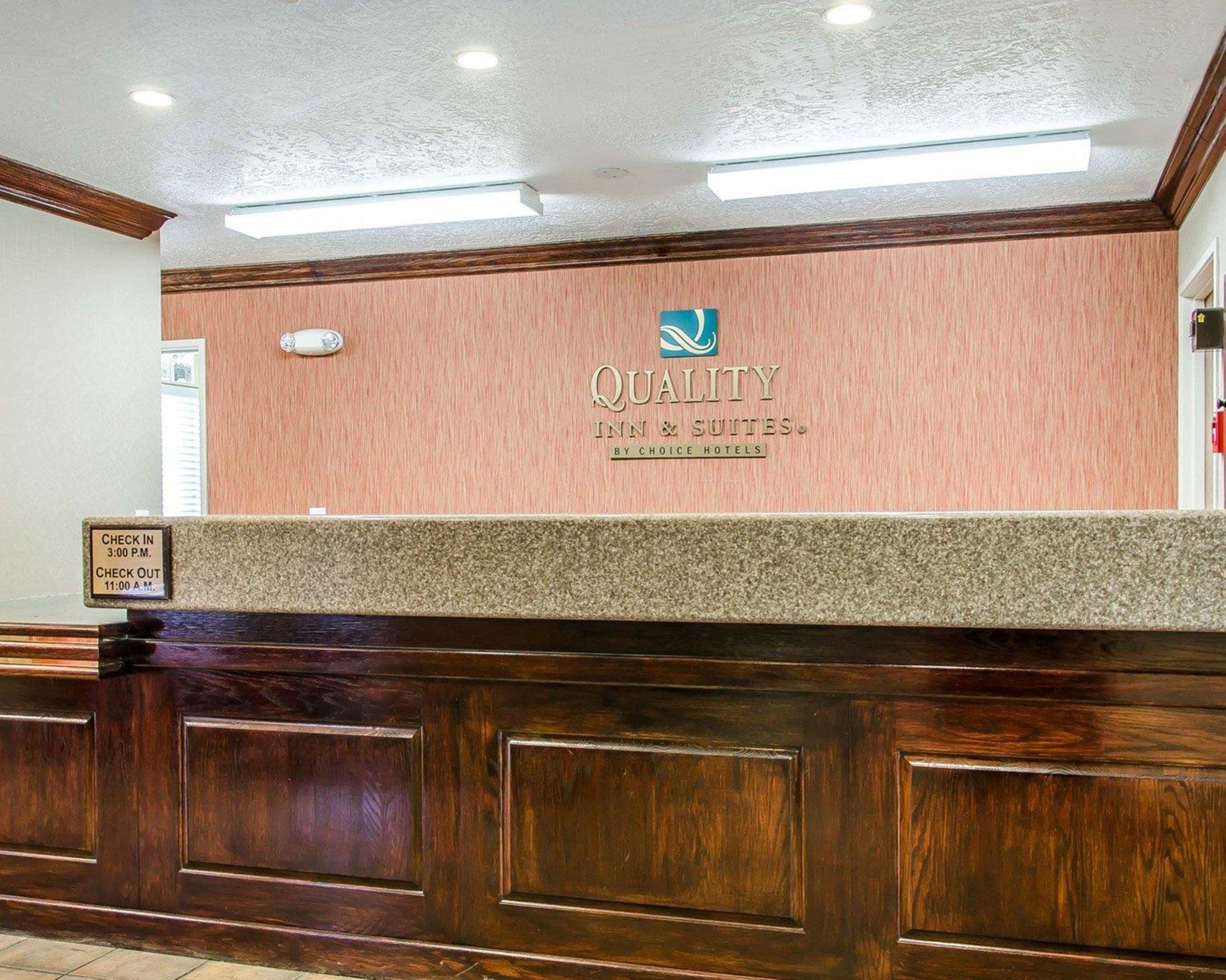A reception desk with a sign reading "QUALITY INN & SUITES BY CHOICE HOTELS".