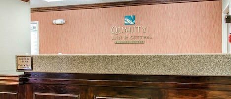 A reception desk with a sign reading "QUALITY INN & SUITES BY CHOICE HOTELS".