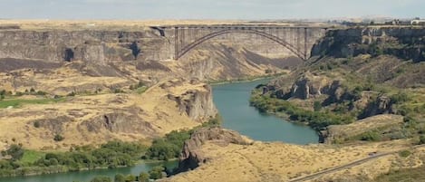 Un puente sobre un río, con un valle y vegetación en primer plano.