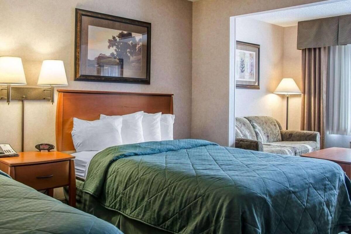 A hotel room with a bed, bedside lamps, a desk with a phone, and a chair.