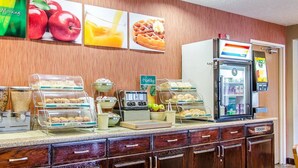 Een ontbijtbuffet met diverse etenswaren, een koelkast en een fruitsapautomaat.