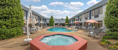 A hotel with two pools, a hot tub, and outdoor seating.
