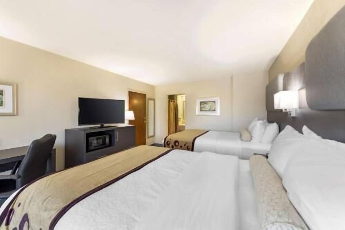 Une chambre d’hôtel avec deux lits, une télévision, un bureau et une porte.