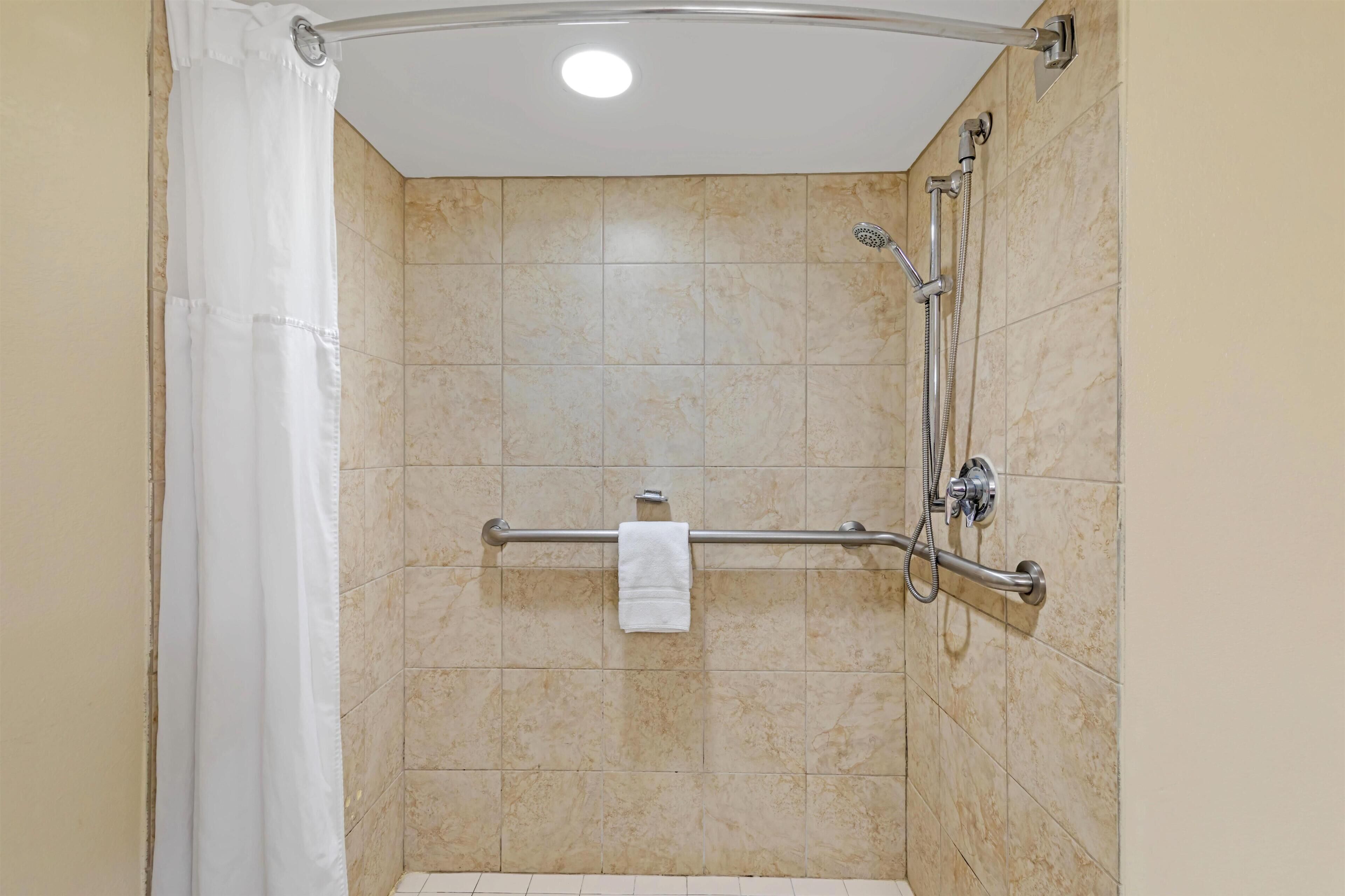 A shower with a grab bar, a towel rack, and a showerhead.