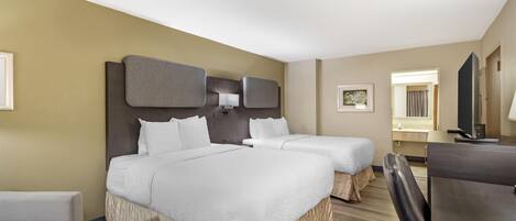 A hotel room with two beds, a desk, a chair, a television, and a framed picture on the wall.
