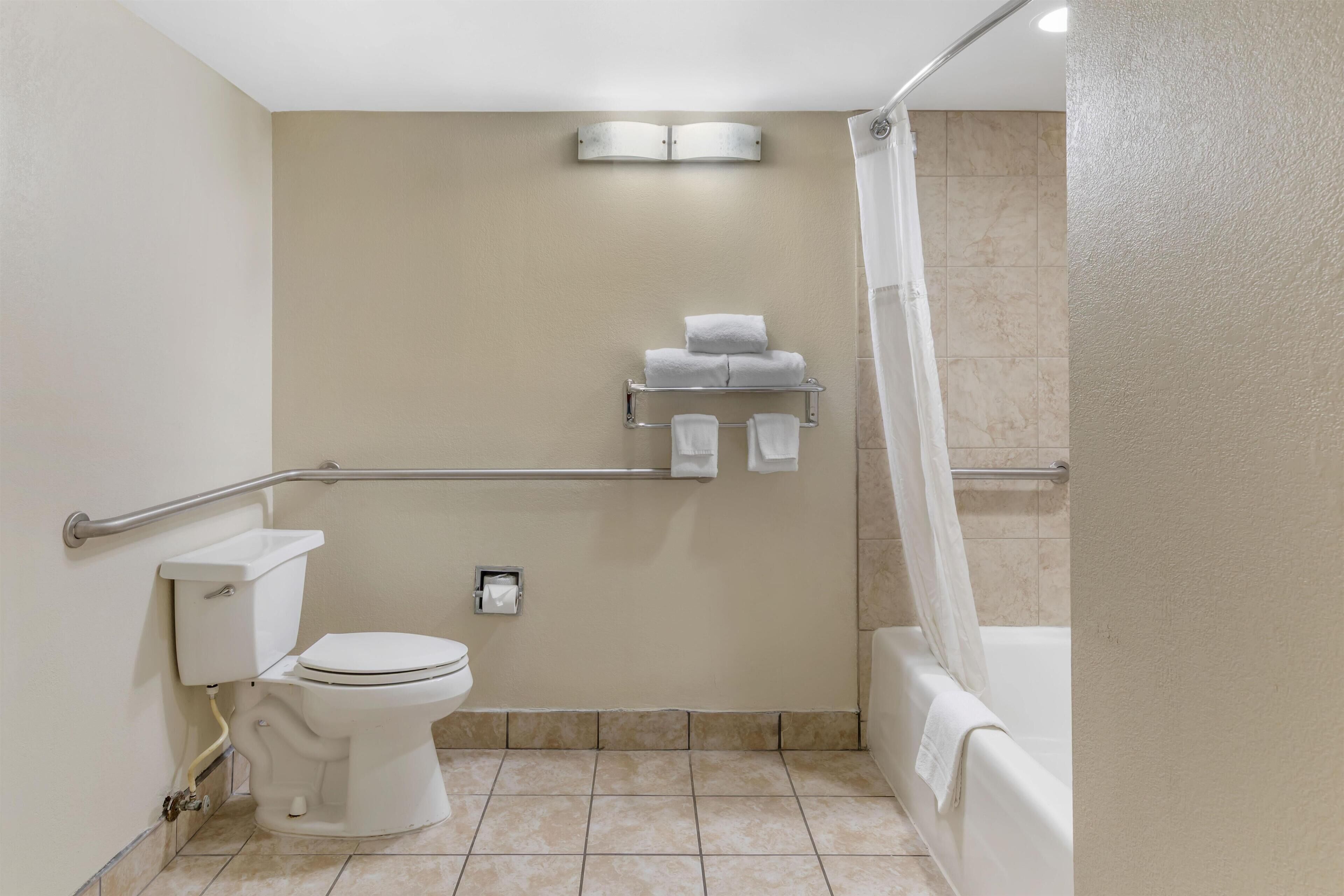 Une salle de bain comprenant des toilettes, un lavabo, une douche avec un rideau et un porte-serviettes avec des serviettes.