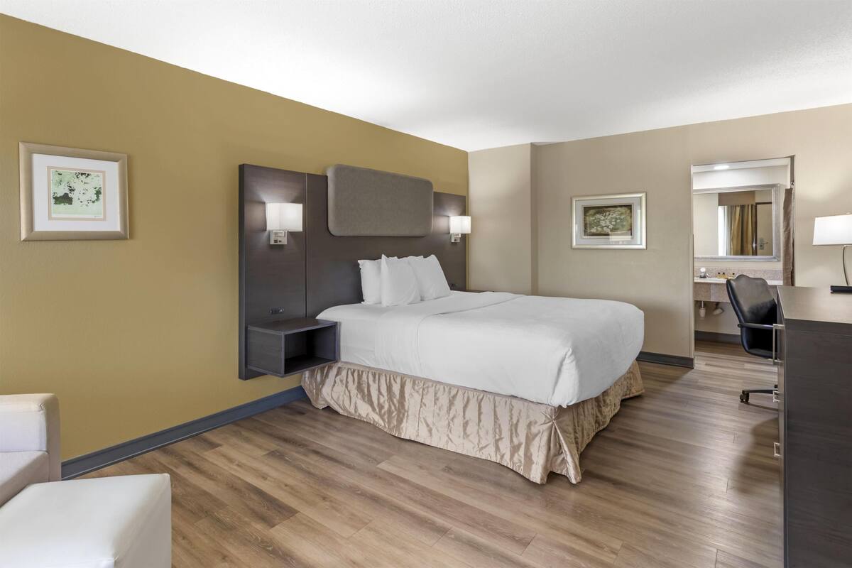 Une chambre d’hôtel avec un grand lit, des tables de chevet, un bureau, une chaise et un miroir.