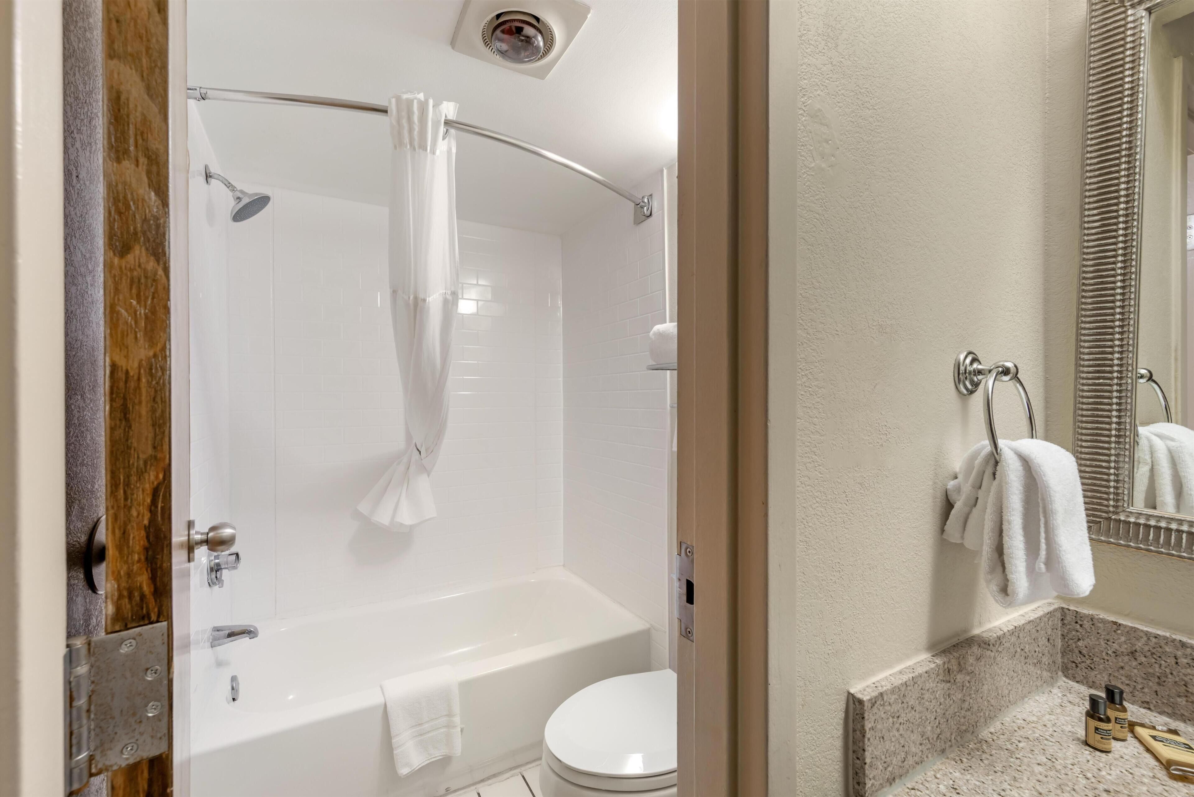 Une salle de bain avec une baignoire, des toilettes et un rideau de douche.