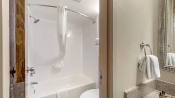 A bathroom with a bathtub, toilet, and shower curtain.
