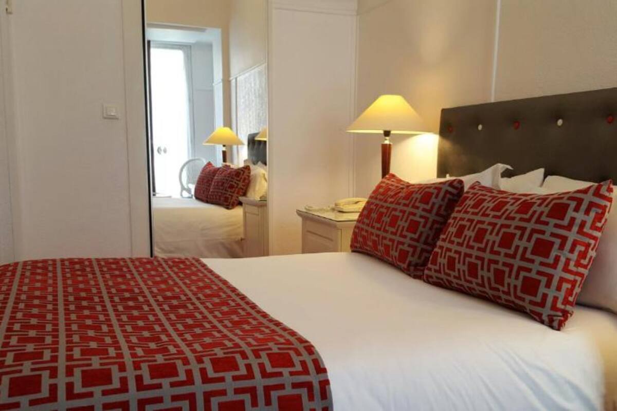Een hotelkamer met een groot bed, twee bedlampen en een spiegel.