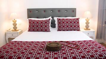 Ein ordentlich bezogenes Bett mit einem gemusterten Überwurf, zwei Kissen mit geometrischem Muster und eine Nachttischlampe auf jeder Seite.