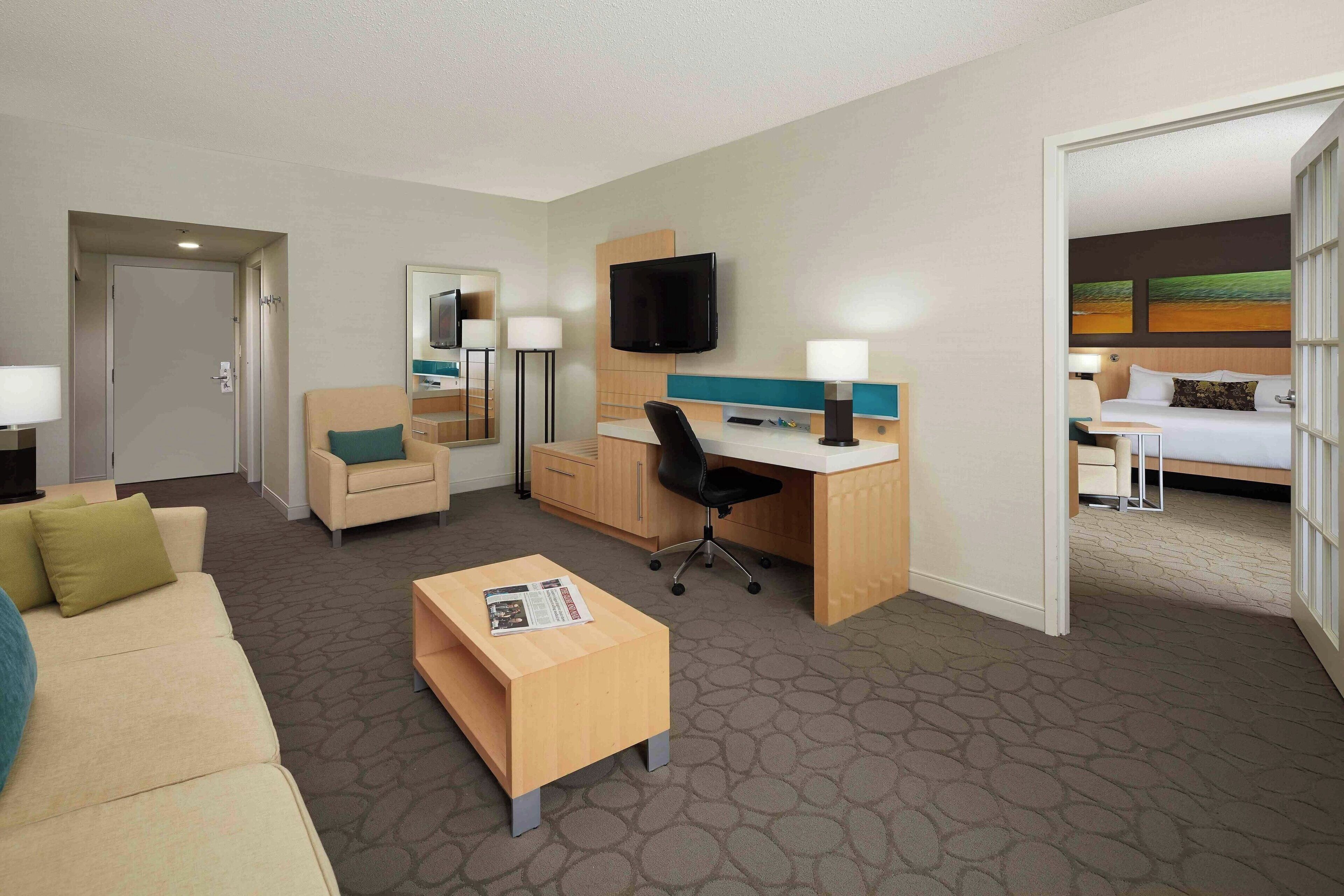Una habitación de hotel con sofá, escritorio, silla, televisor y cama.