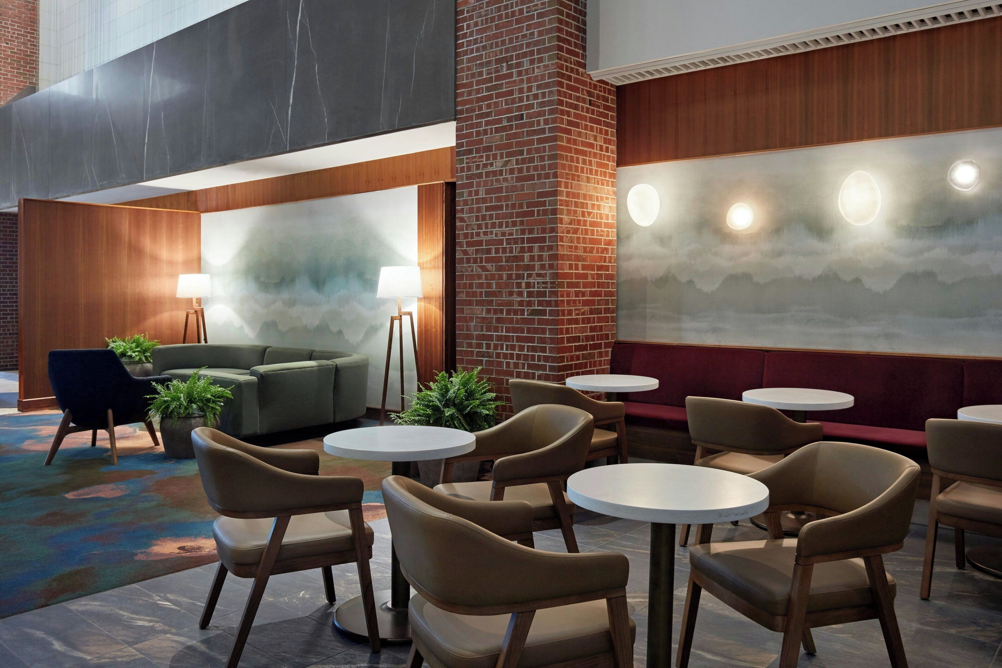A modern lounge area with round tables, cushioned seating, and a large abstract mural on the wall.