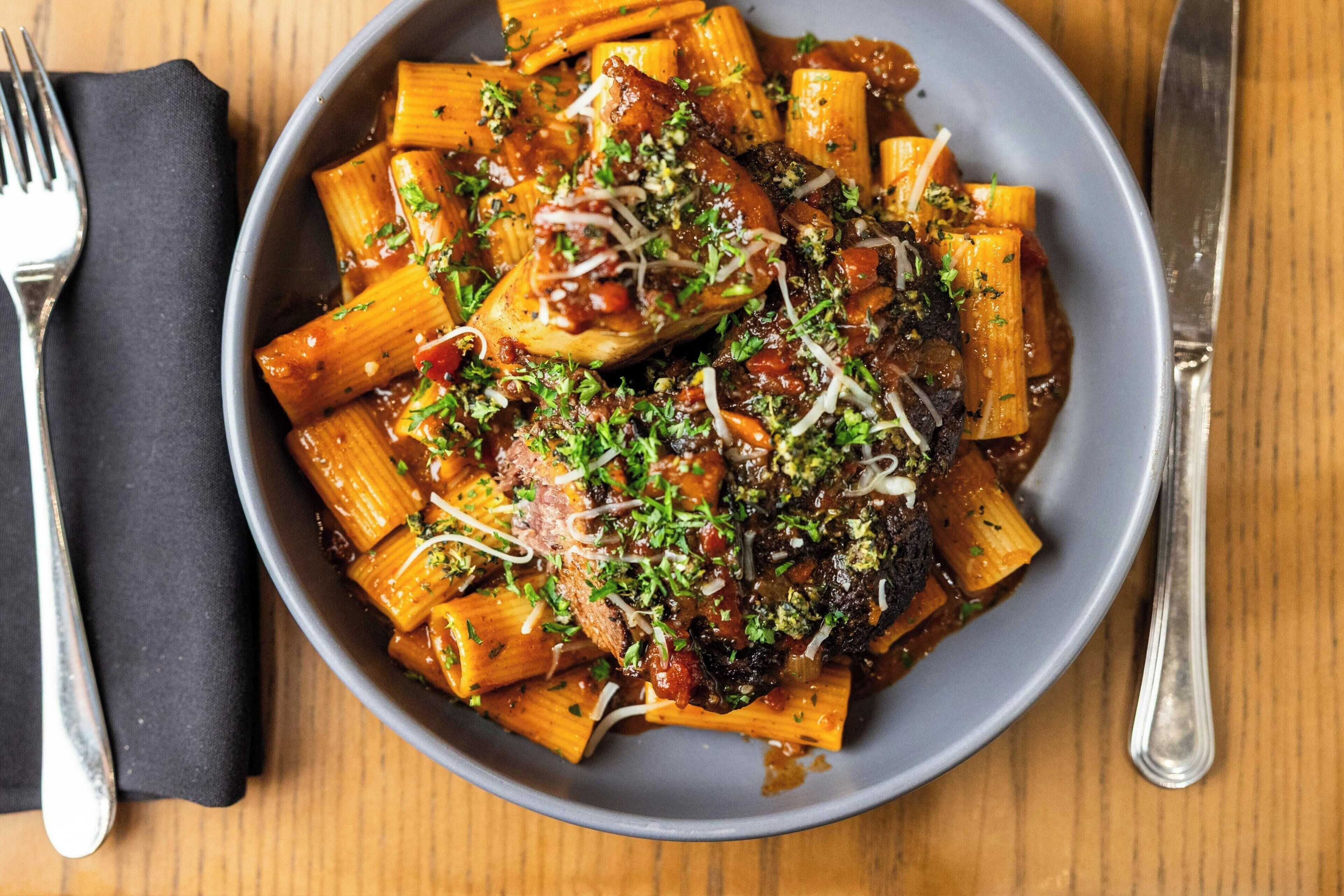 Un plato de pasta con salsa de tomate, adornado con hierbas y queso rallado.