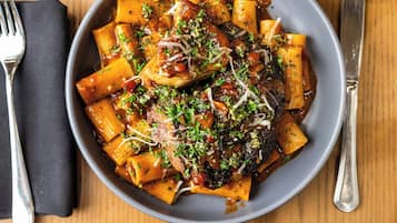 Un plato de pasta con salsa de tomate, adornado con hierbas y queso rallado.
