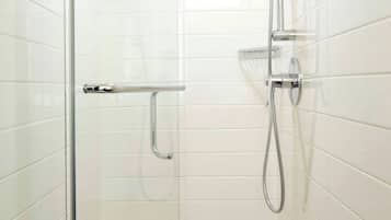 Eine moderne Dusche mit Handbrause und fest installierter Duschbrause, einer Glasduschwand und einer Metall-Haltestange.