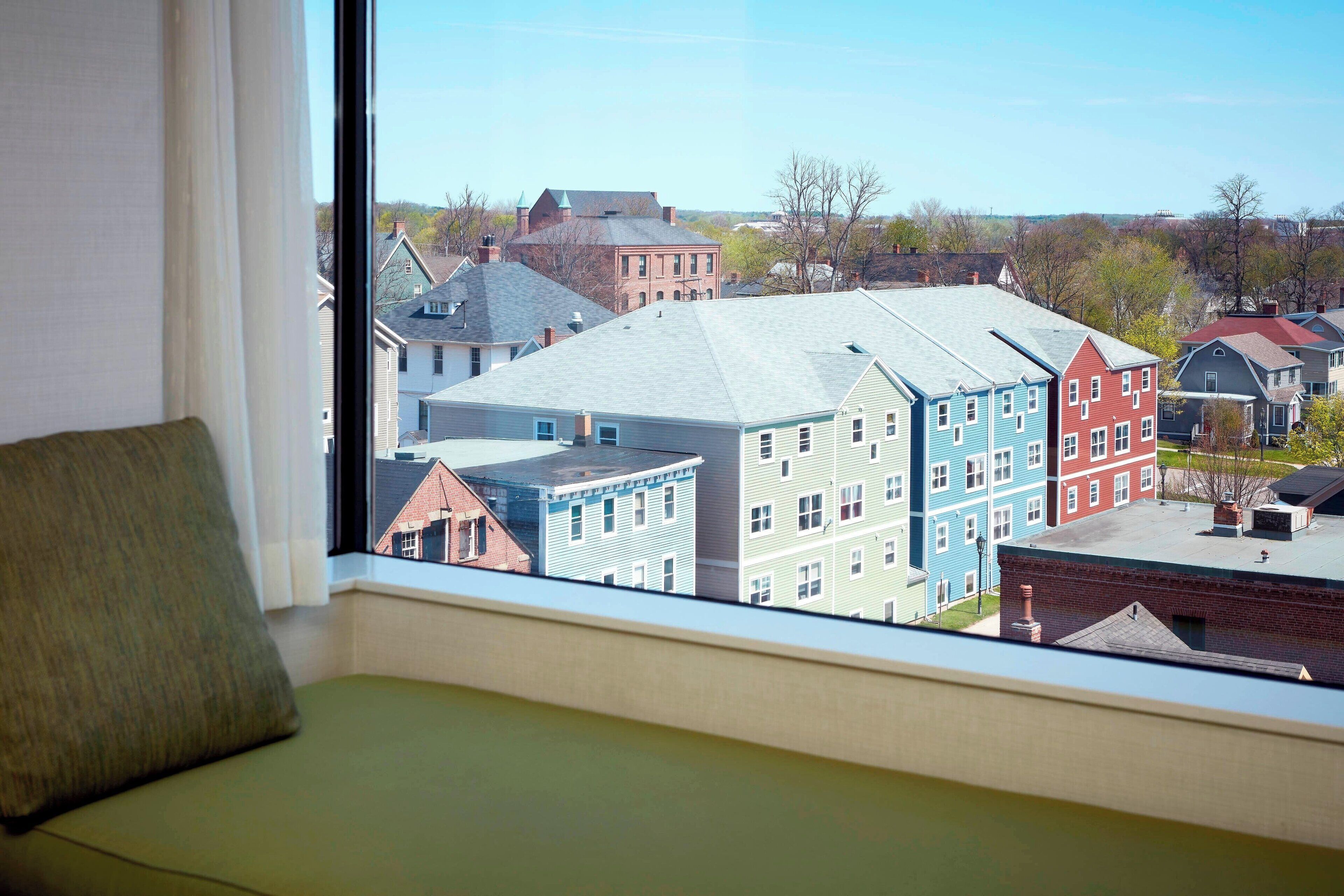 A room with a large window overlooking a row of colorful buildings.