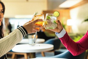 Two people toasting with drinks in a well-lit indoor setting. - Delta Hotels Prince Edward by Marriott (Charlottetown)