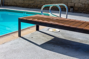 Una piscina al aire libre, sillones reclinables de piscina