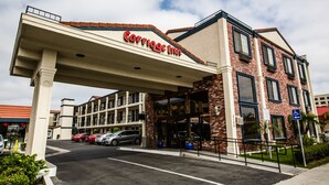 A Carrige Inn hotel with a brick facade, multiple windows, and a covered entrance. - Anaheim Carriage Inn (Anaheim)