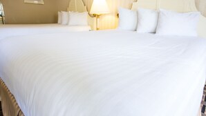 A hotel room with two beds, a headboard, a lamp, and a framed picture on the wall. - Anaheim Carriage Inn (Anaheim)