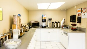 A kitchen with a microwave, coffee maker, and juice dispenser. - Anaheim Carriage Inn (Anaheim)