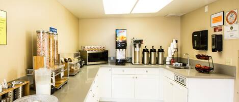 Une cuisine équipée d’un four à micro-ondes, d’une machine à café et d’un distributeur de jus.