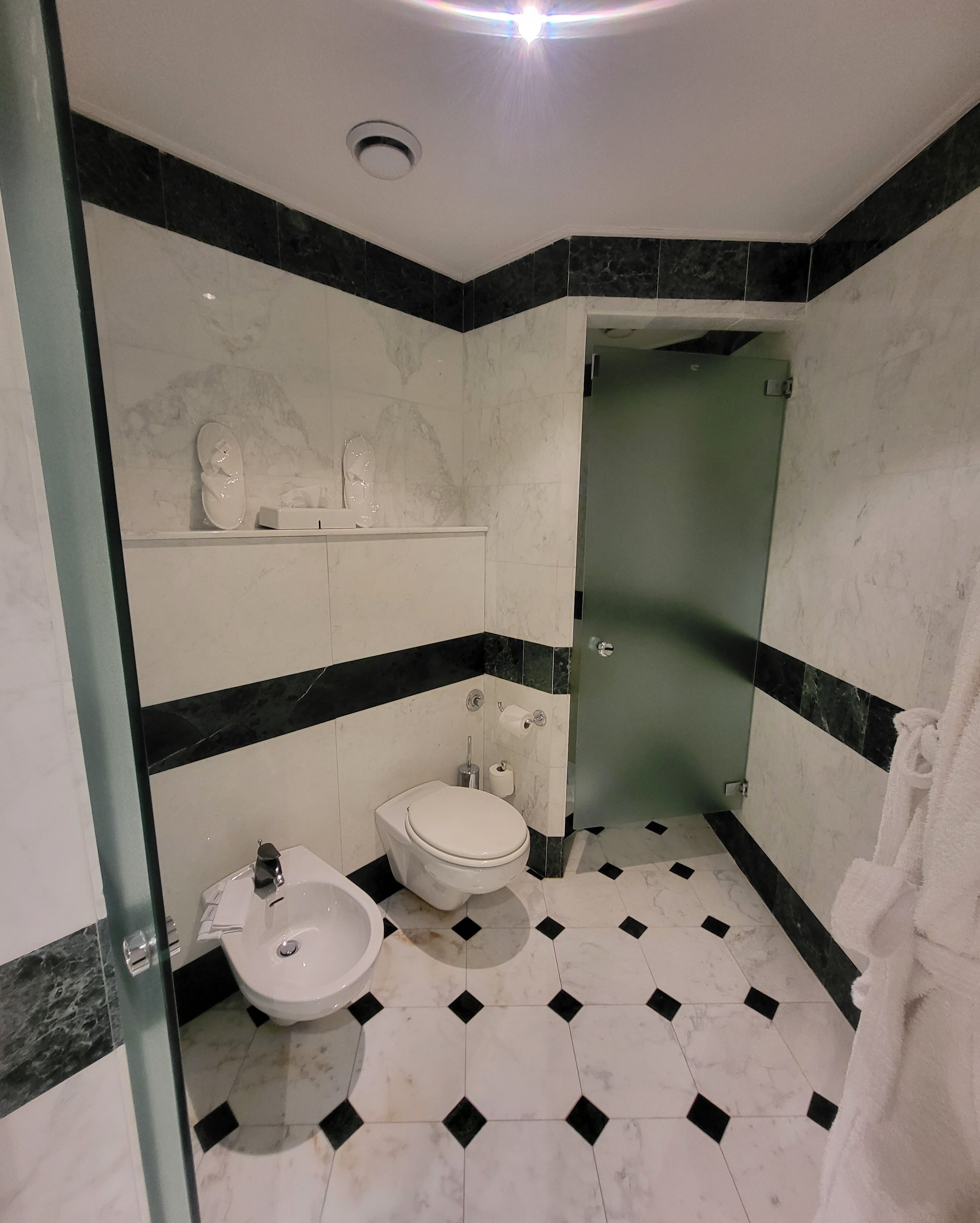 Une salle de bain équipée de toilettes, d’un lavabo et d’une douche à parois de verre.