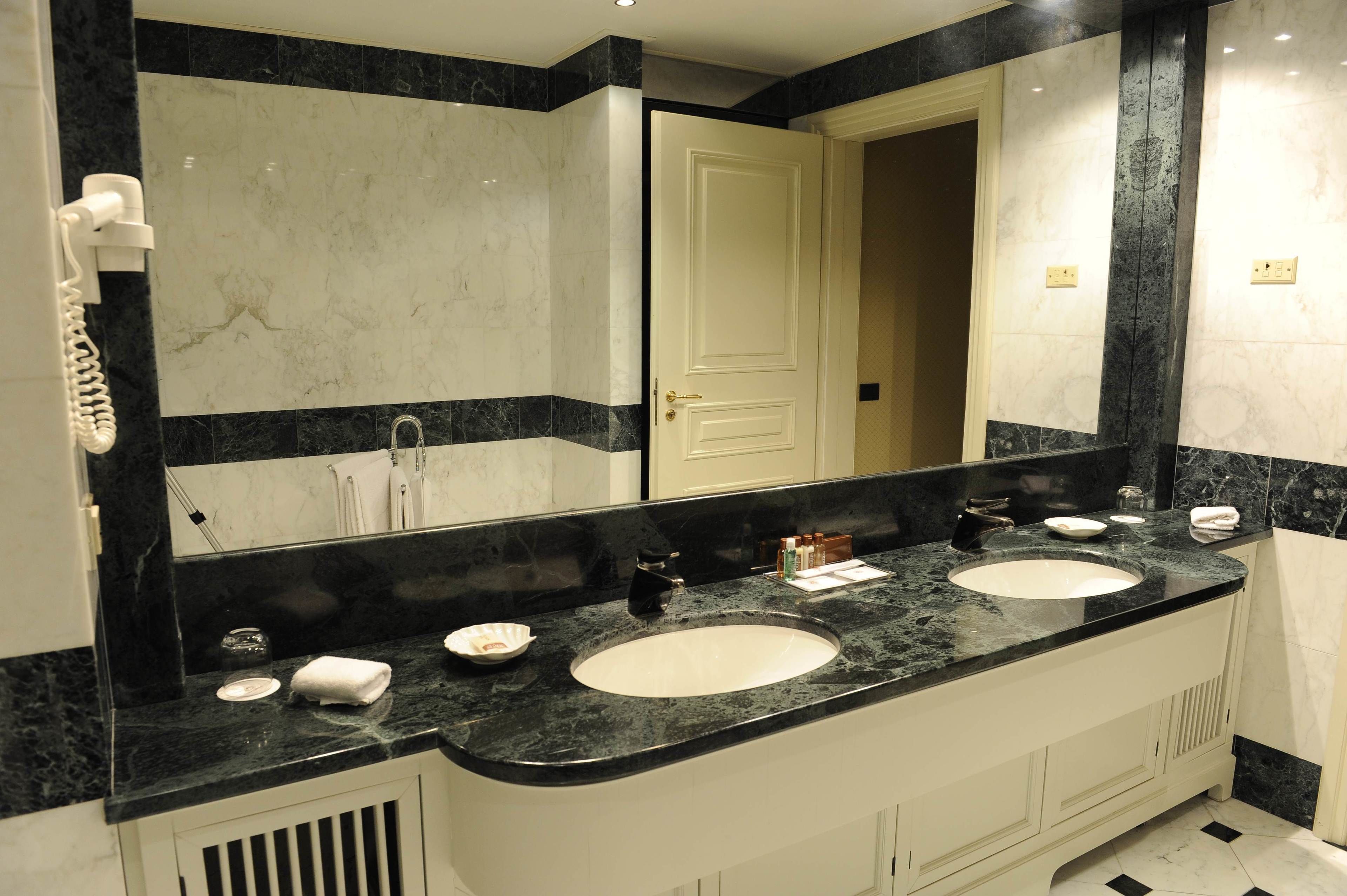 Une salle de bain avec deux lavabos, un grand miroir et un sèche-cheveux fixé au mur.