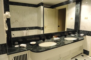 Une salle de bain avec deux lavabos, un grand miroir et un sèche-cheveux fixé au mur.