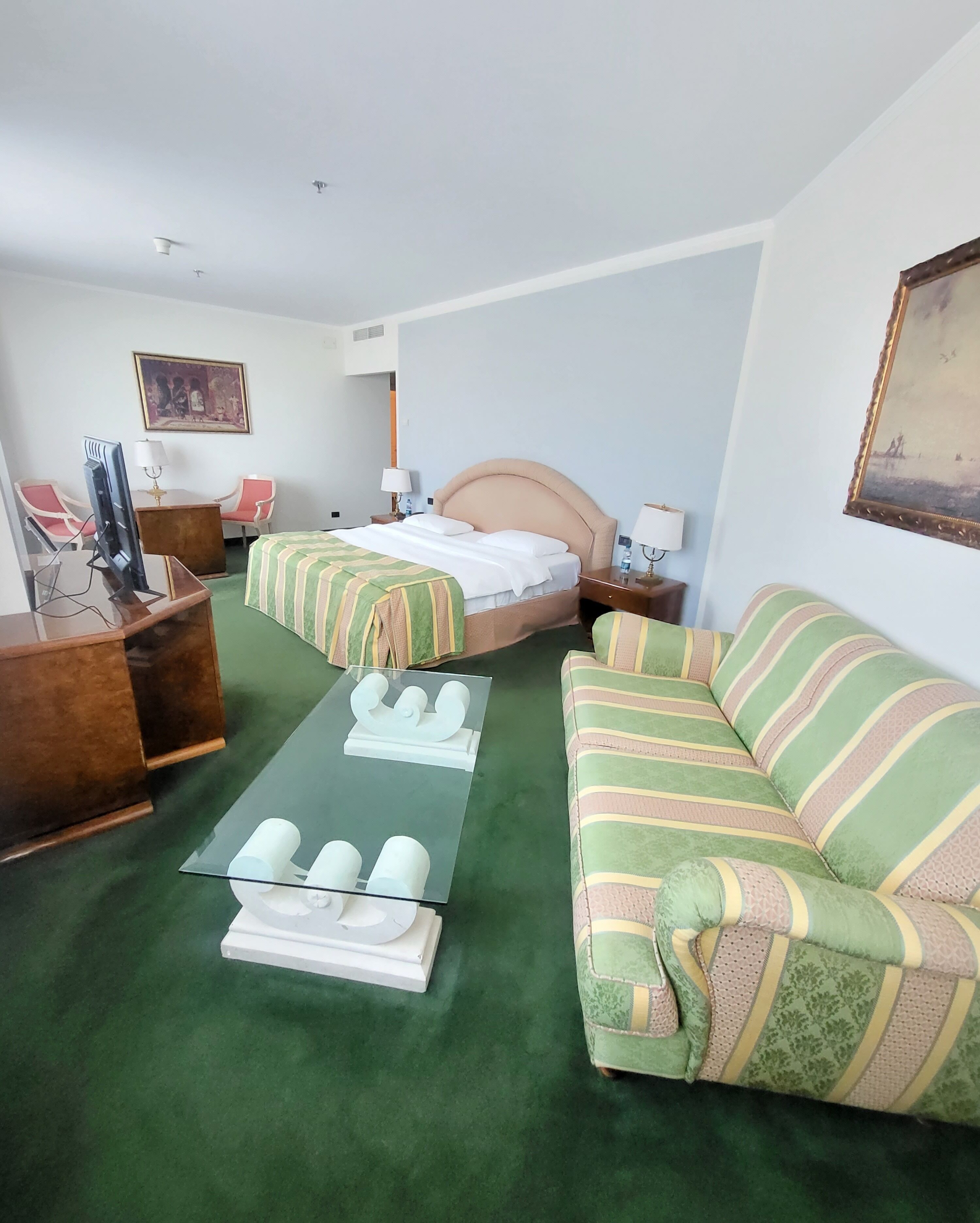 A hotel room with a bed, a sofa, a desk with a computer, and a chair.