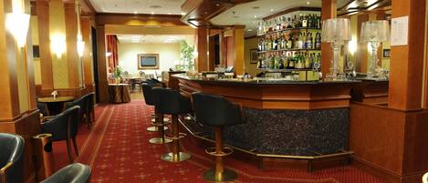 A bar area with a counter, bar stools, and a carpeted floor.