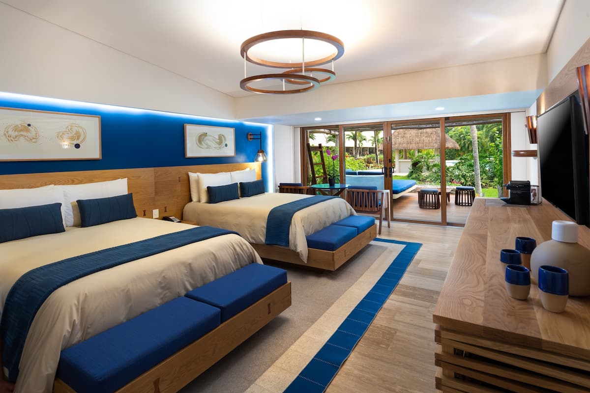 Une chambre d’hôtel moderne avec deux lits, un coin repas et une vue sur le jardin.
