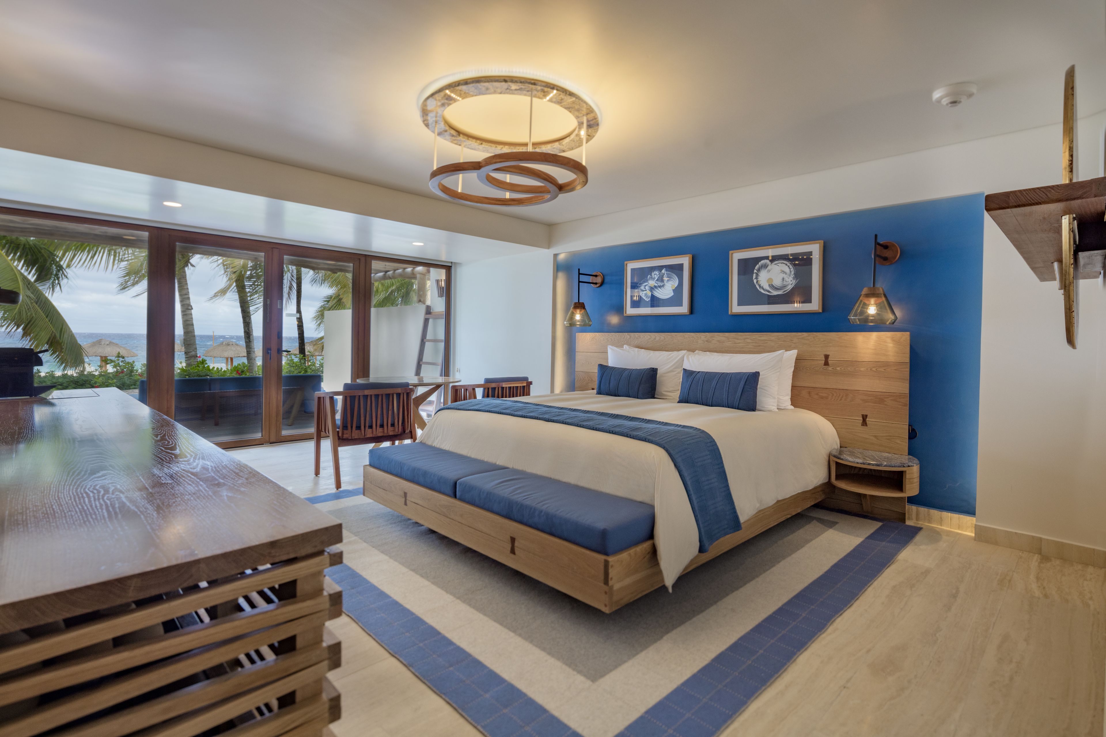 Een moderne slaapkamer met een groot bed, een houten bureau en uitzicht op de oceaan.