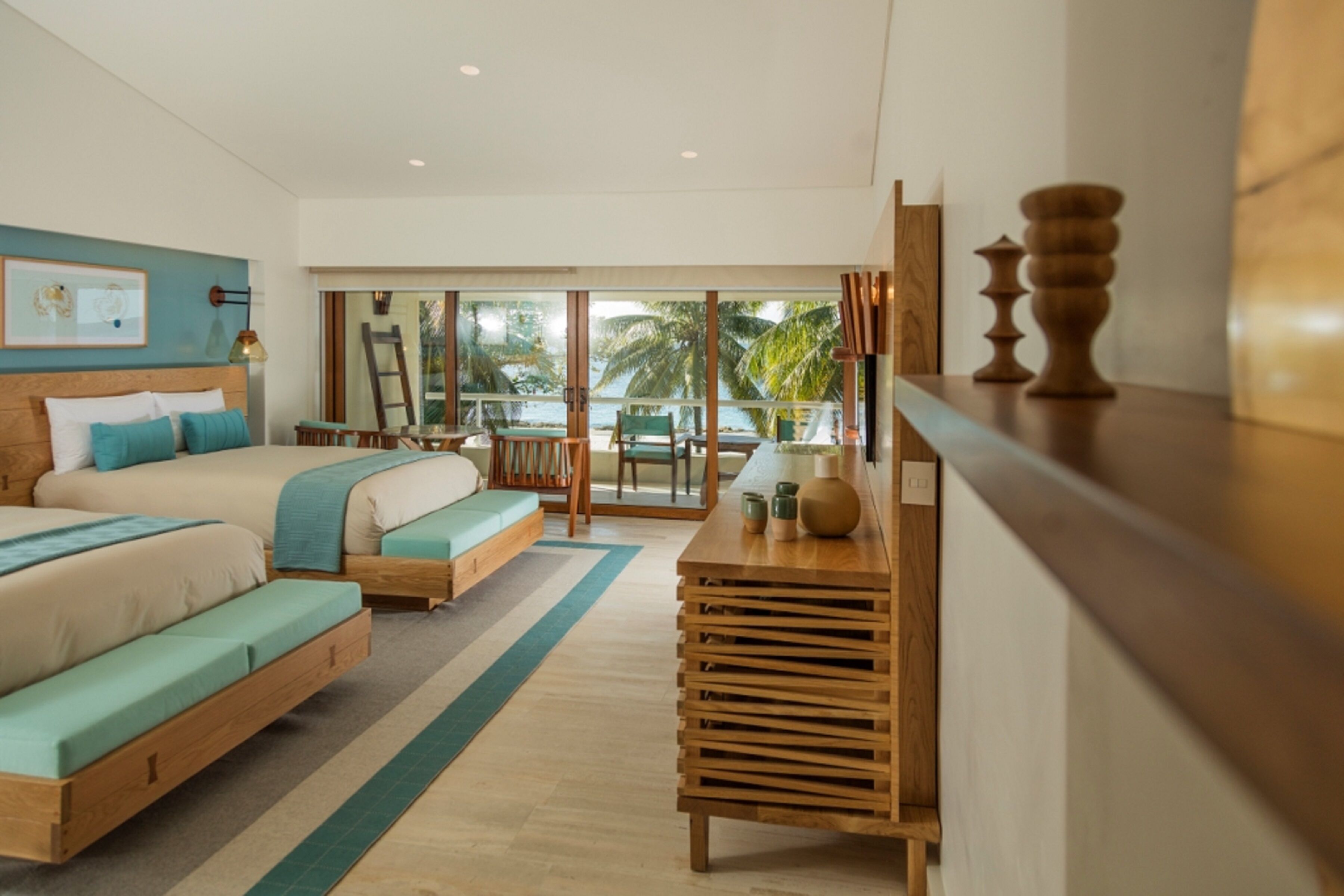 A modern hotel room with a large bed, a desk, and a view of the ocean.