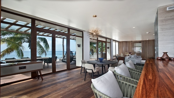 Een modern interieur met een houten vloer, een ronde eettafel en een zithoek met uitzicht op de oceaan.