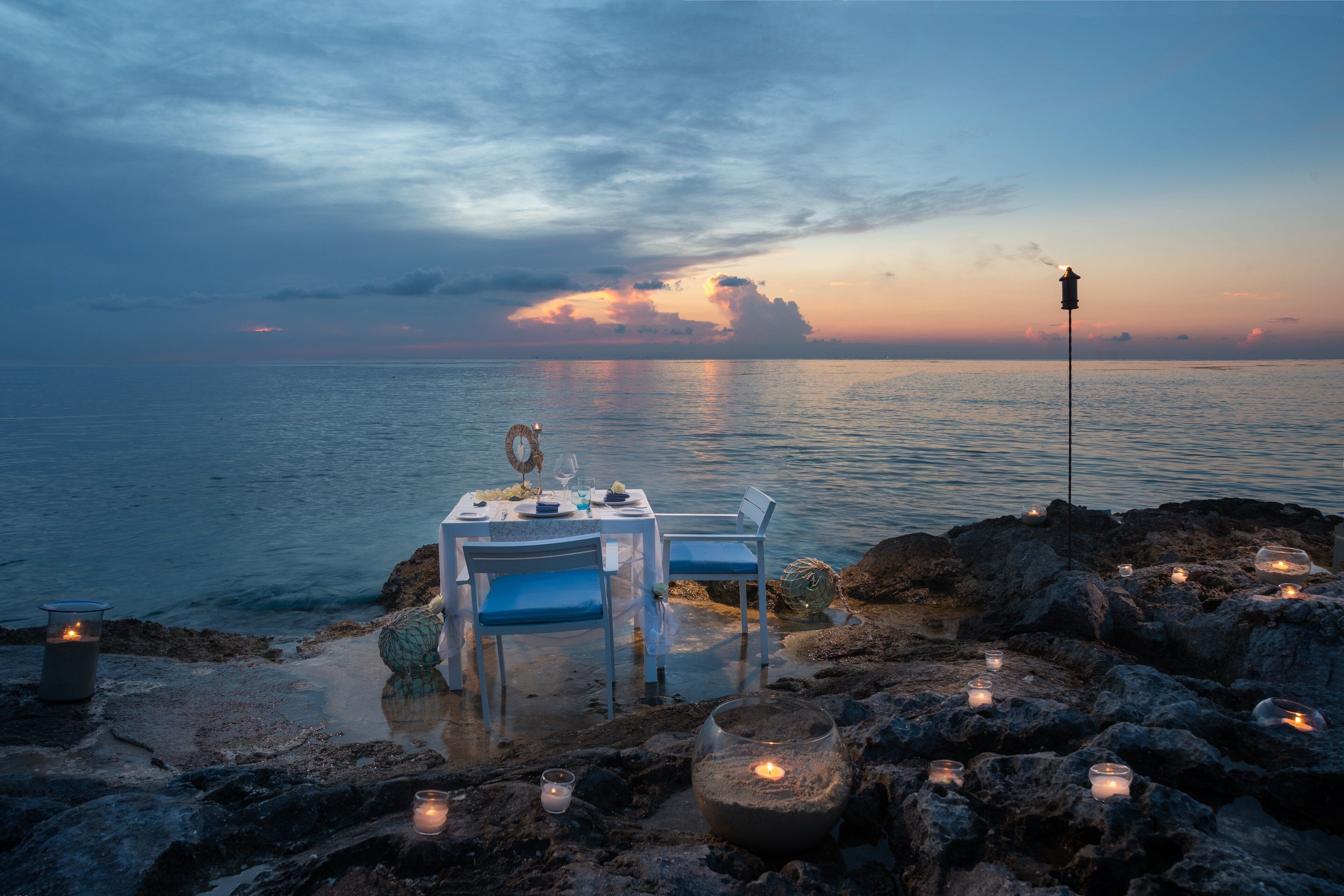 A table set for two with a view of the sea at sunset.